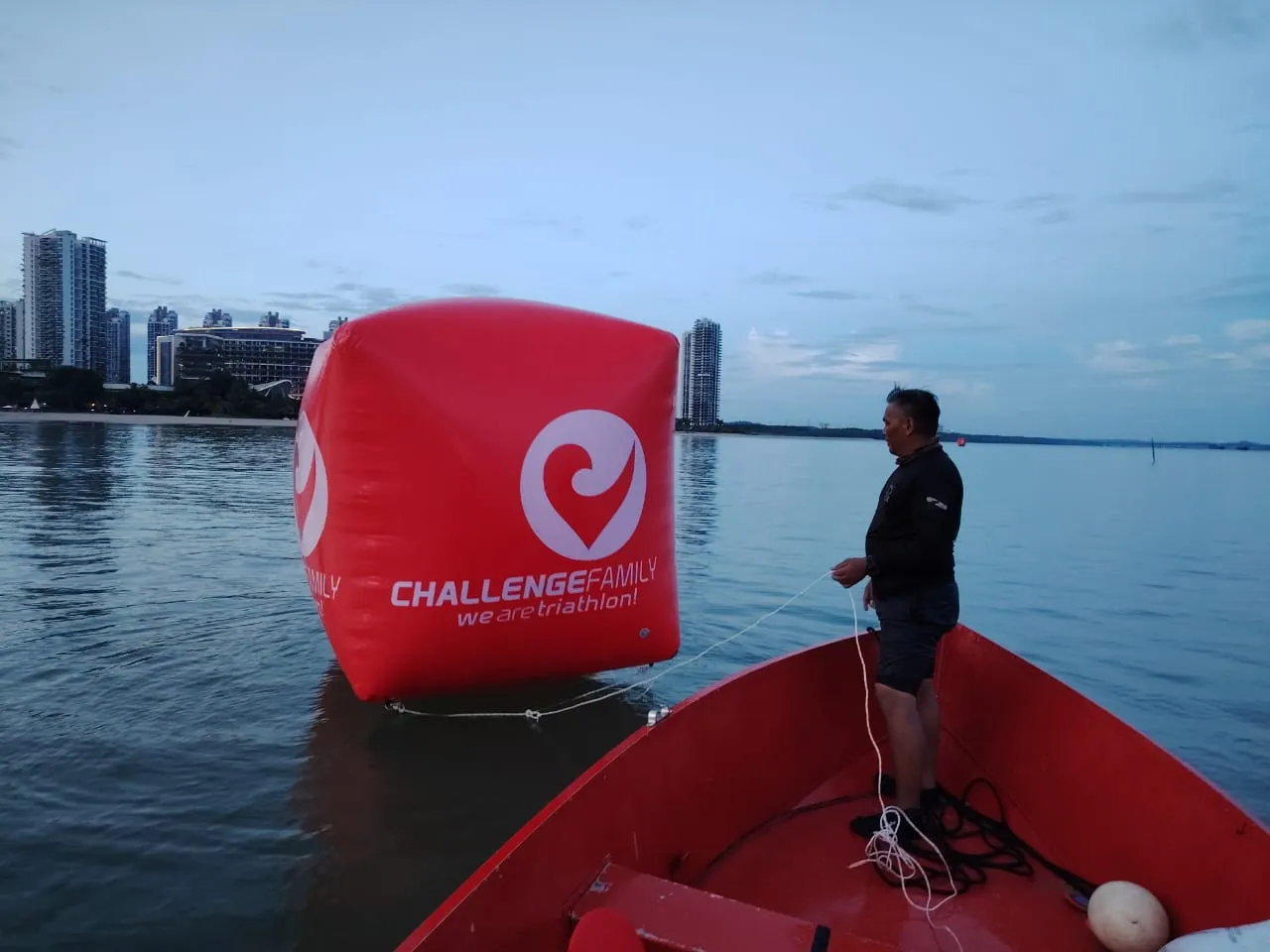 TIZ Events crew positioning a Challenge Family triathlon swim buoy at dusk